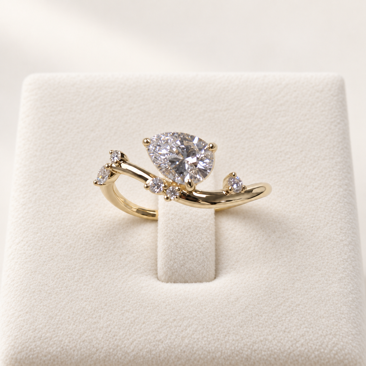 Arden Flame pear diamond ring in yellow gold, front view on an ivory display