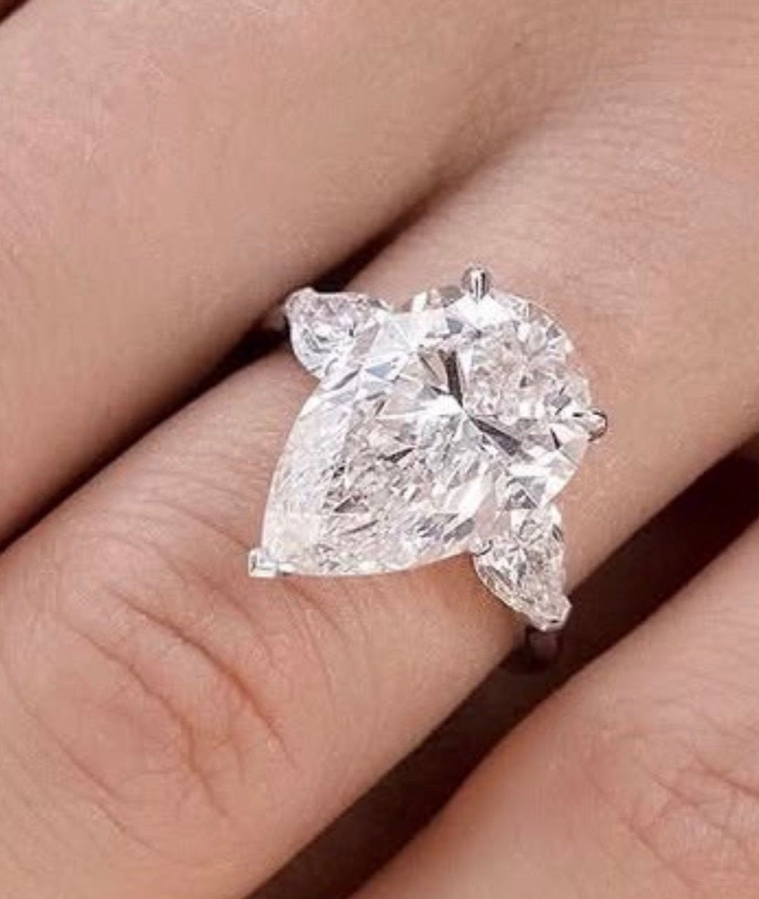 On-hand design reference for The Vivienne showing a pear centre and two pear side stones. The photograph is a design reference, not a verified finished silver or gold option.