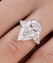 On-hand design reference for The Vivienne showing a pear centre and two pear side stones. The photograph is a design reference, not a verified finished silver or gold option.