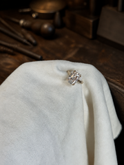 Isolde’s Secret ring on white jeweller’s linen at a dark rustic workbench, front view