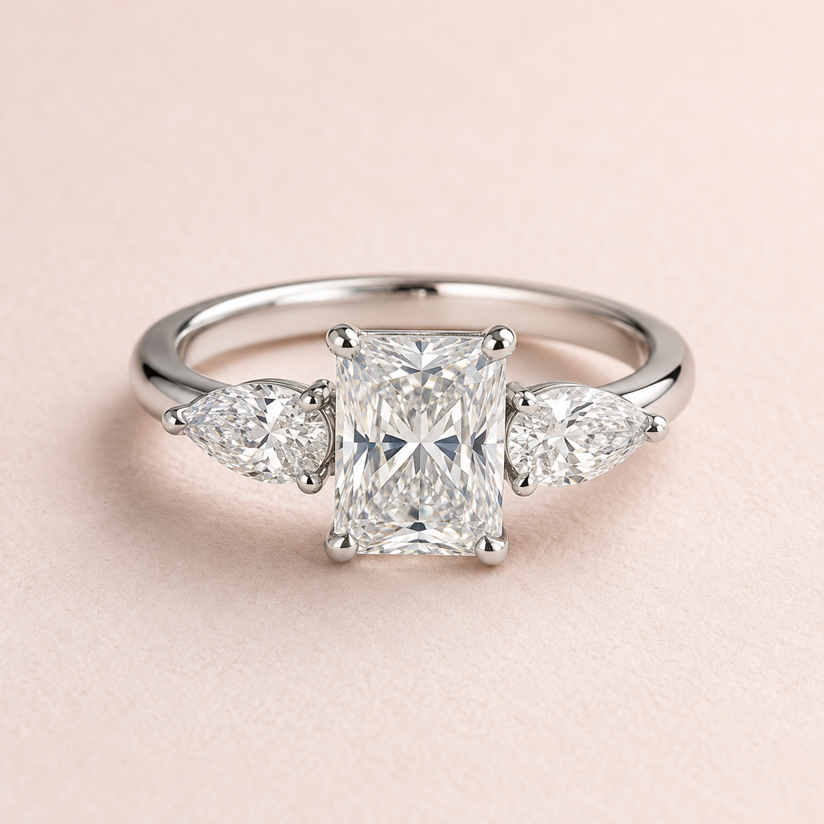 Lumera Passage radiant-centre ring with pear side stones — existing silver-tone design illustration, used temporarily; not a photograph of the finished silver and moissanite edition.
