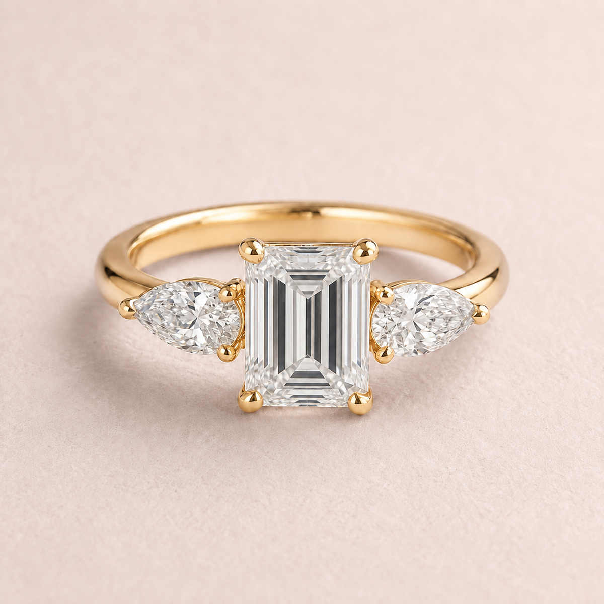 Lumera Passage three-stone ring concept with an emerald-cut centre and pear-shaped side stones in yellow gold