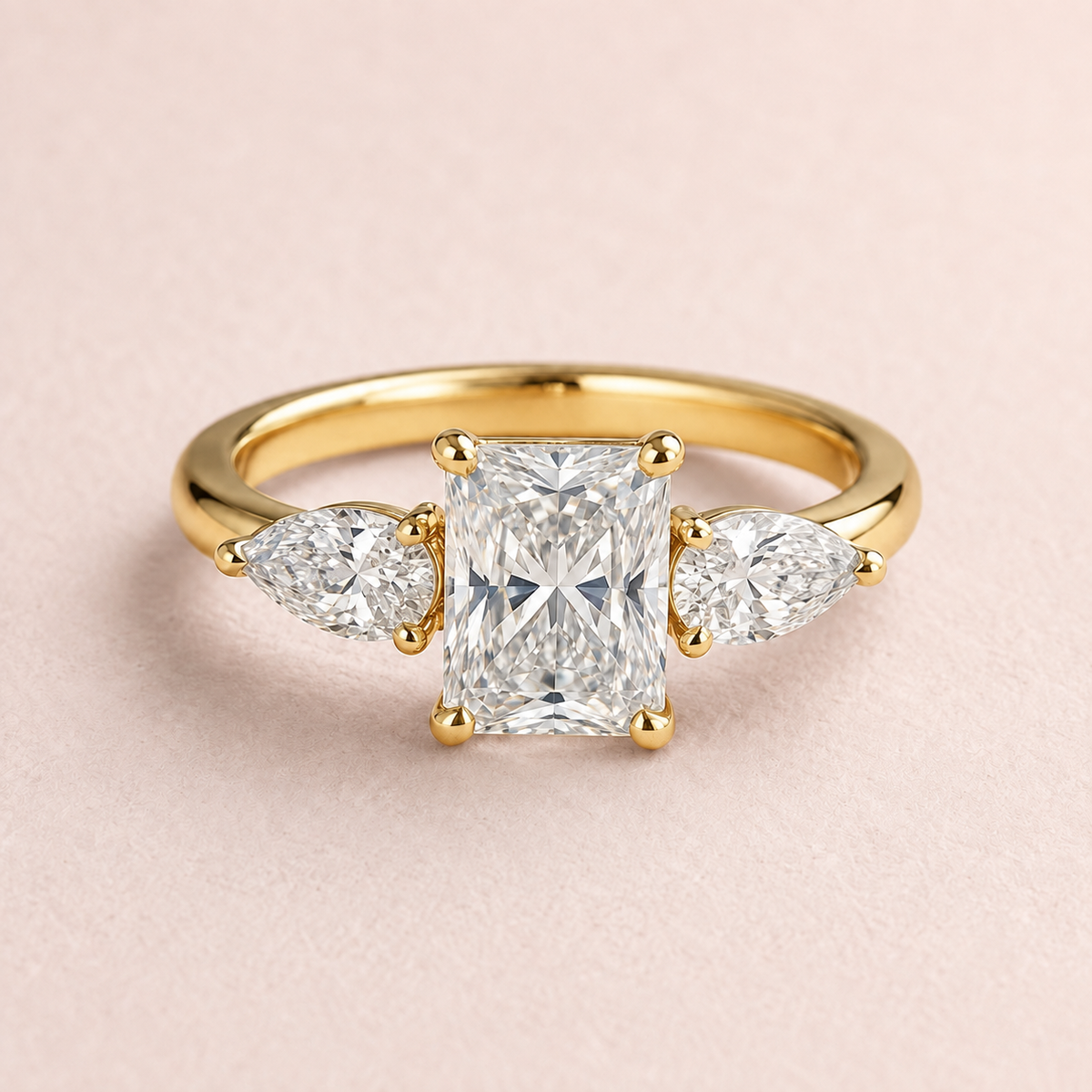 Lumera Passage three-stone ring concept with a radiant-cut centre and pear-shaped side stones in yellow gold