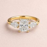Lumera Passage three-stone ring concept with a radiant-cut centre and pear-shaped side stones in yellow gold