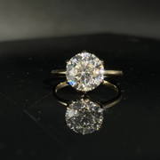 Olivia's Ovation round brilliant lab-grown diamond ring, centred front view on polished black Perspex