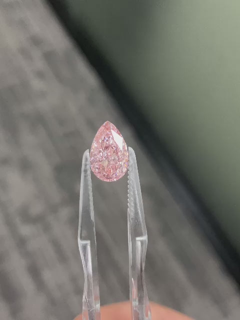 Loose pear-shaped pink lab-grown diamond reference held in tweezers