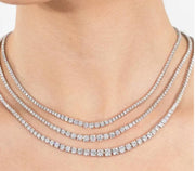 Three graduated diamond tennis necklace sizes shown together on the neckline