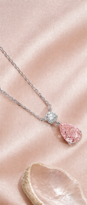 Vela Blush necklace with a Solene-pink pear-shaped lab-grown diamond and white round diamond on blush silk beside a shell