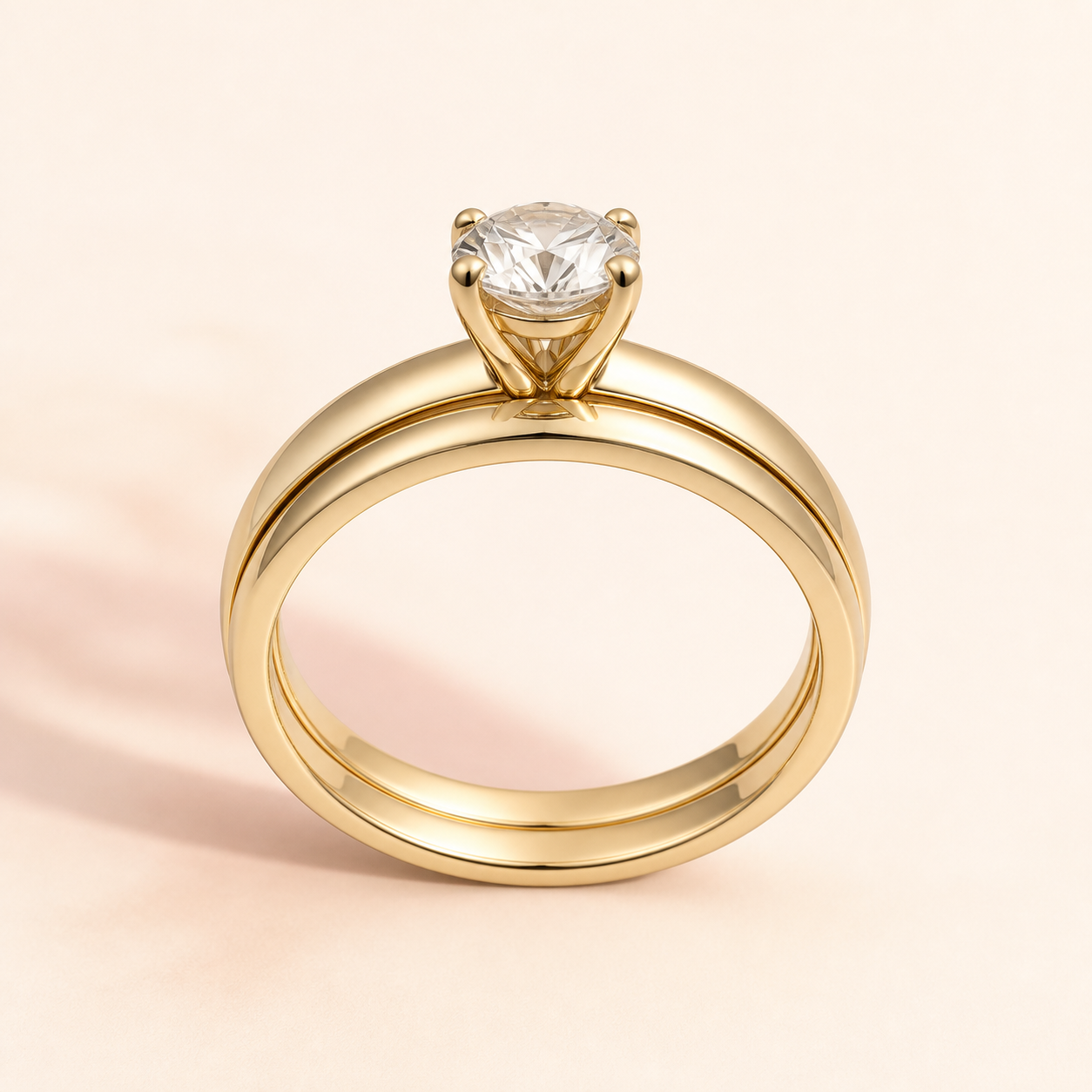 A straight yellow-gold wedding band sitting closely beneath a solitaire engagement ring
